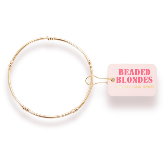 Beaded Blondes Mollie Bar Bracelet in Gold beside a pink jewelry tag.