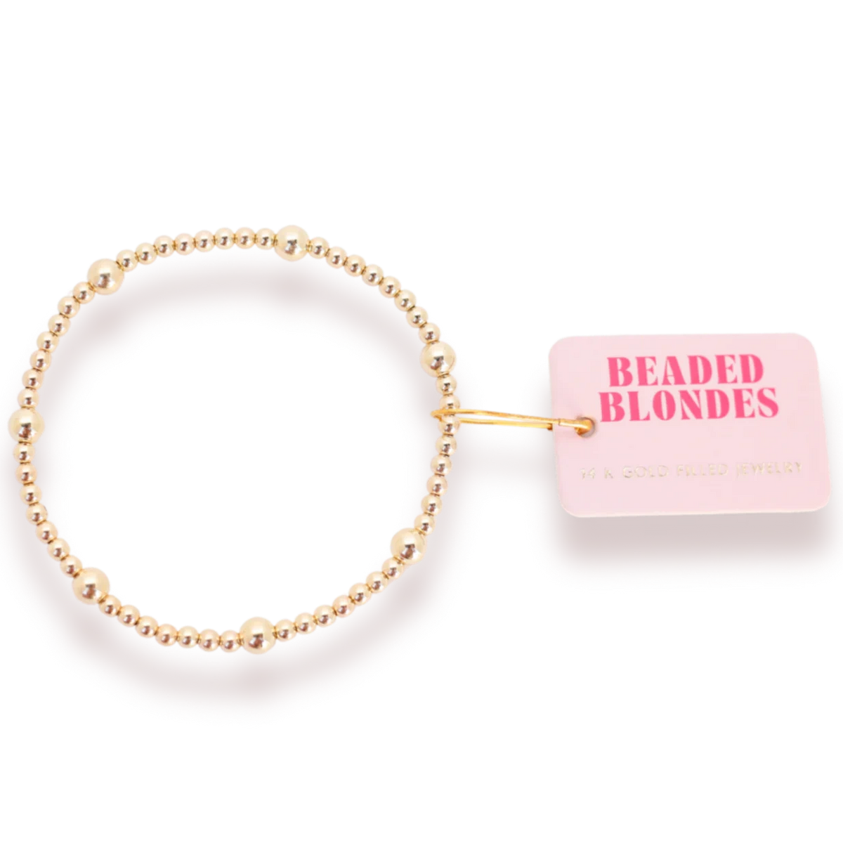 Beaded Blondes Olive Bracelet in Gold arranged in a circle, showing mixed bead sizes beside a pink tag.