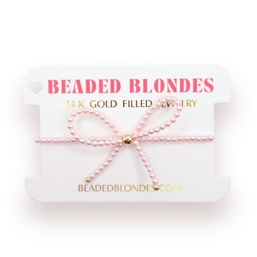 Beaded Blondes Pink Bow Bracelet displayed on a pink jewelry card.