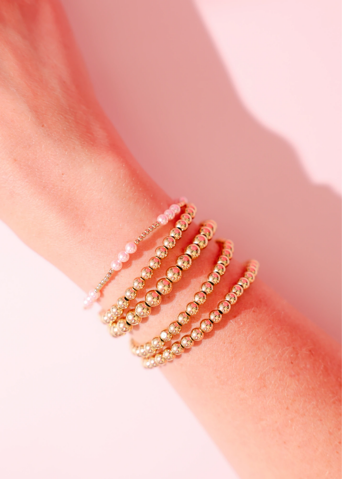 Layered pink and gold bracelets worn together on a wrist.