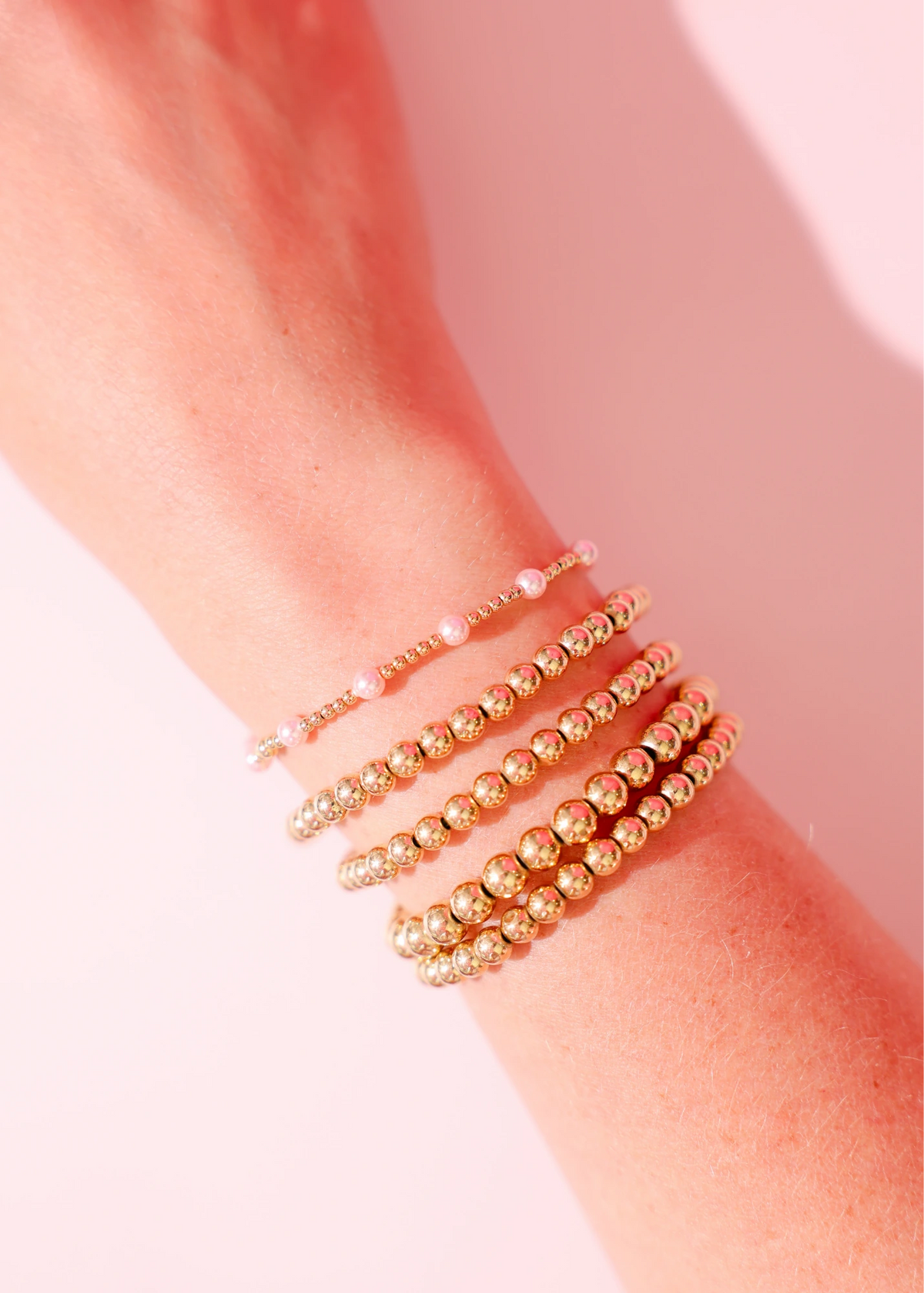 Layered pink and gold bracelets worn together on a wrist.