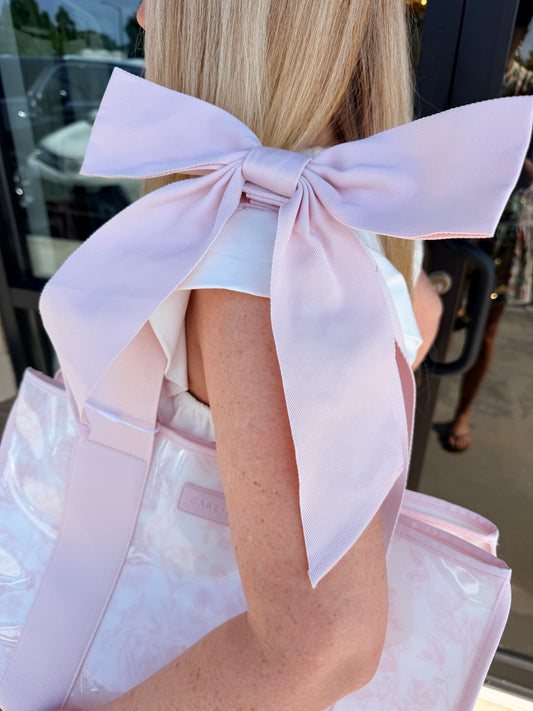 Close-up of a person wearing a light pink dress with a large bow detail.