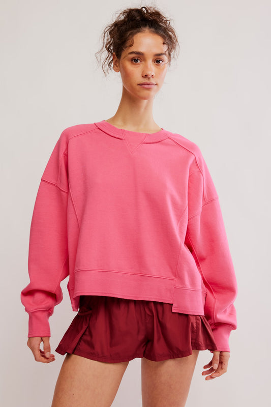 Person wearing a pink sweatshirt and maroon shorts on a light gray background