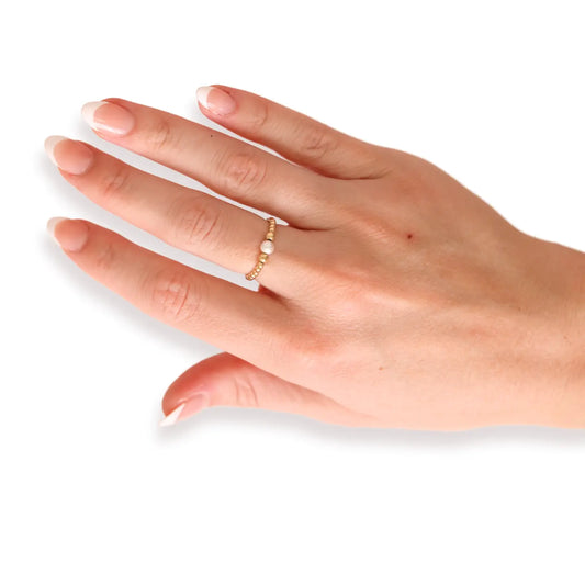 model earring a beaded gold ring with peal in center on middle finger