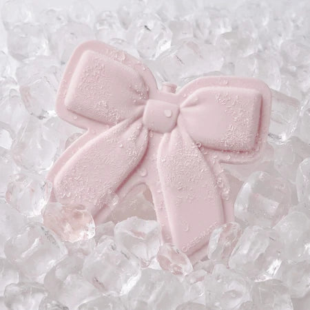 A CASE-MATE pale pink bow-shaped jelly ice pack with water droplets, resting on a bed of clear ice cubes.