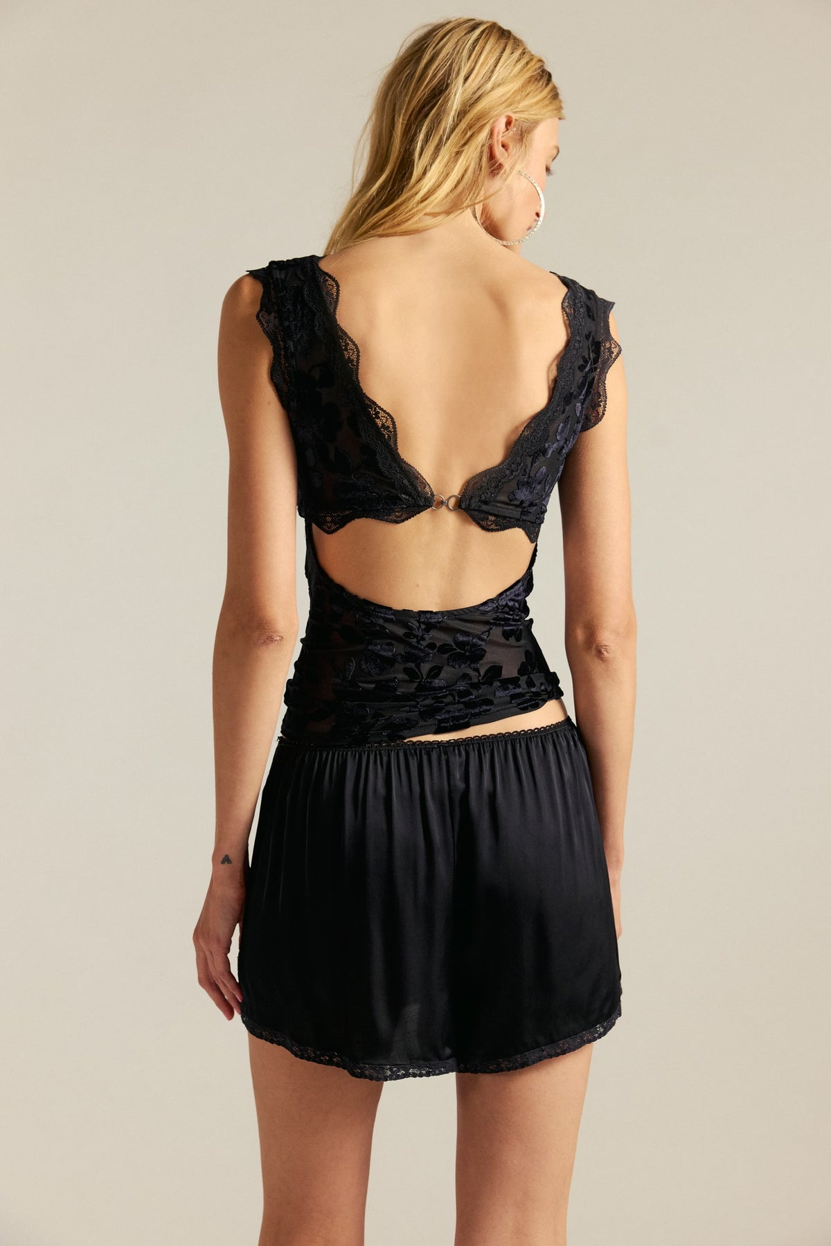 Woman wearing a black lace lingerie set on a beige background