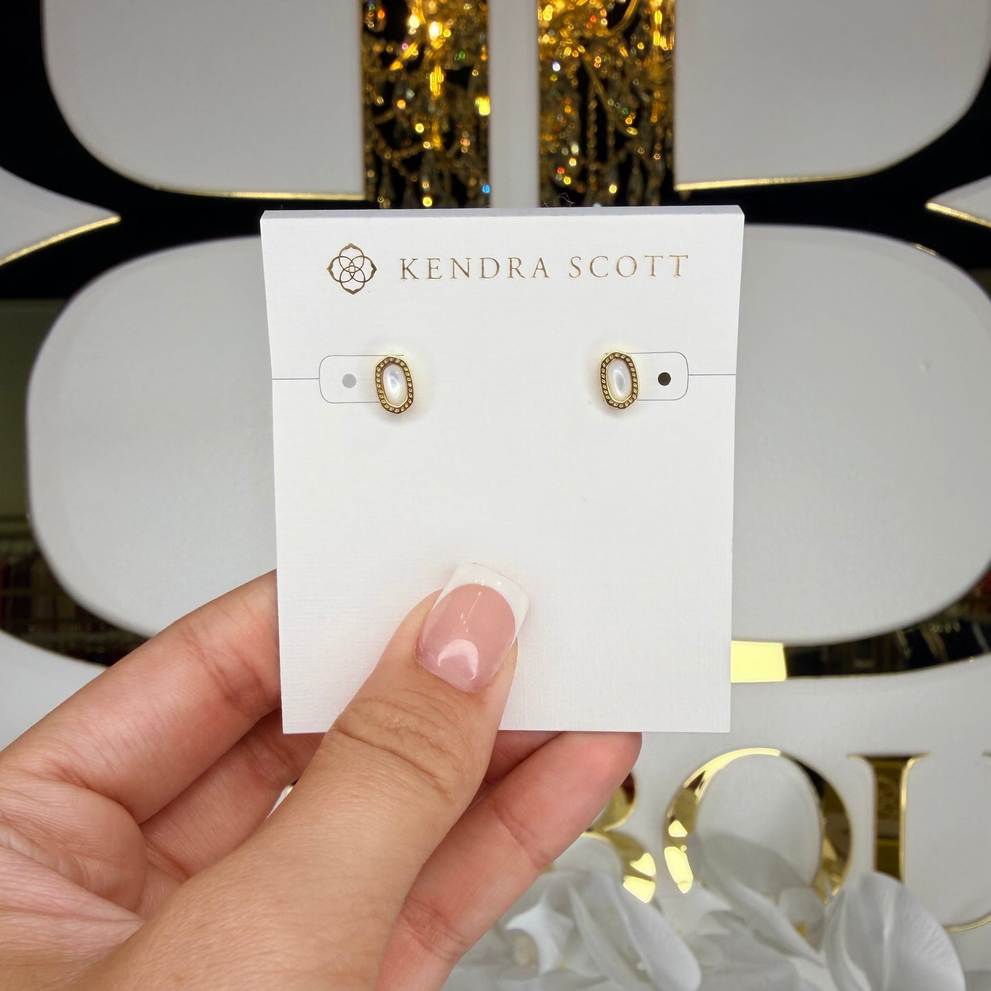 Hand holding a card with earrings on a white background