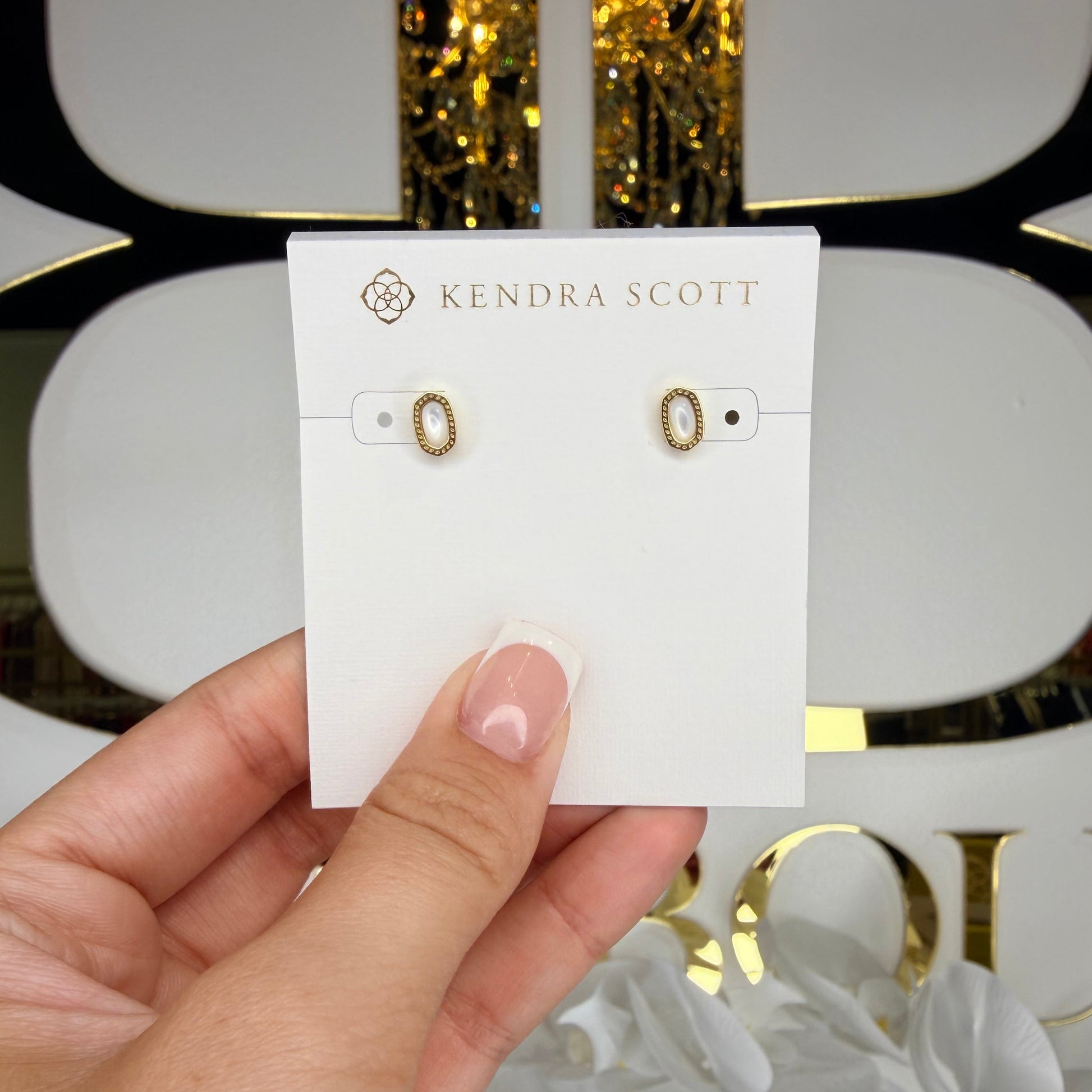 Hand holding a card with earrings on a white background