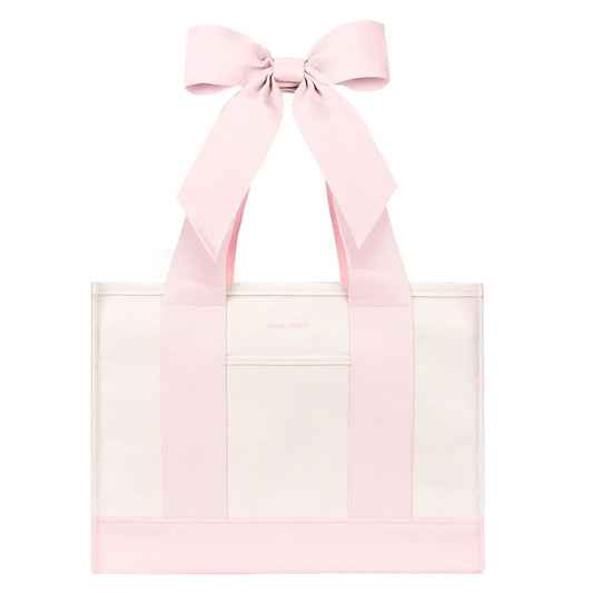 A Case-Mate Bow Canvas Tote Bag Ballet Pink with wide pink shoulder straps forming a large bow at the top, shown on a plain white background.