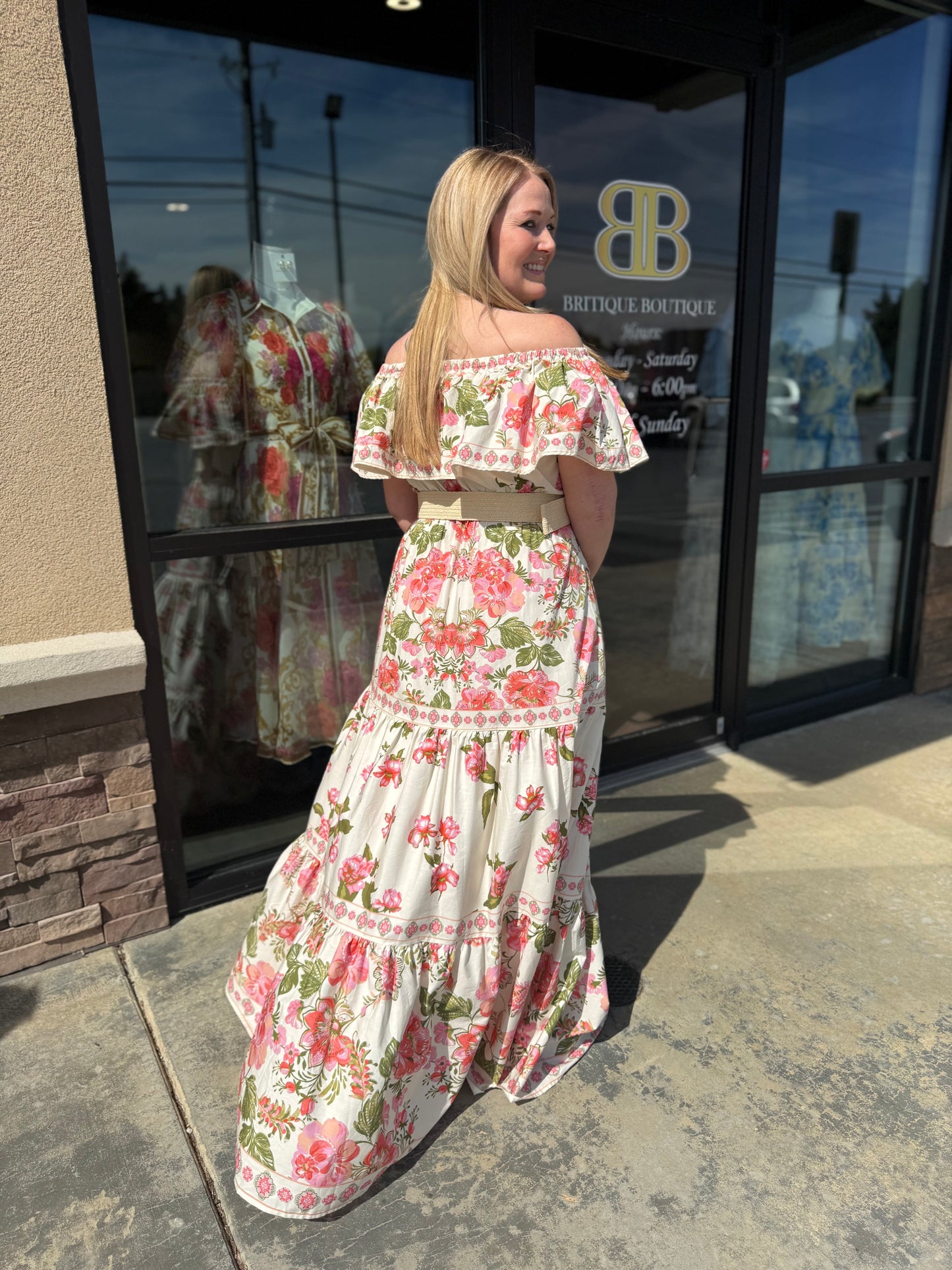 Woman in a floral dress standing outside a boutique store.