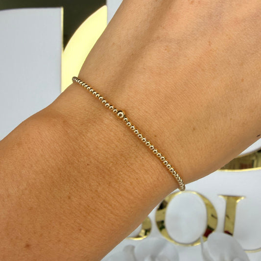 Gold bracelet on a wrist with a decorative background
