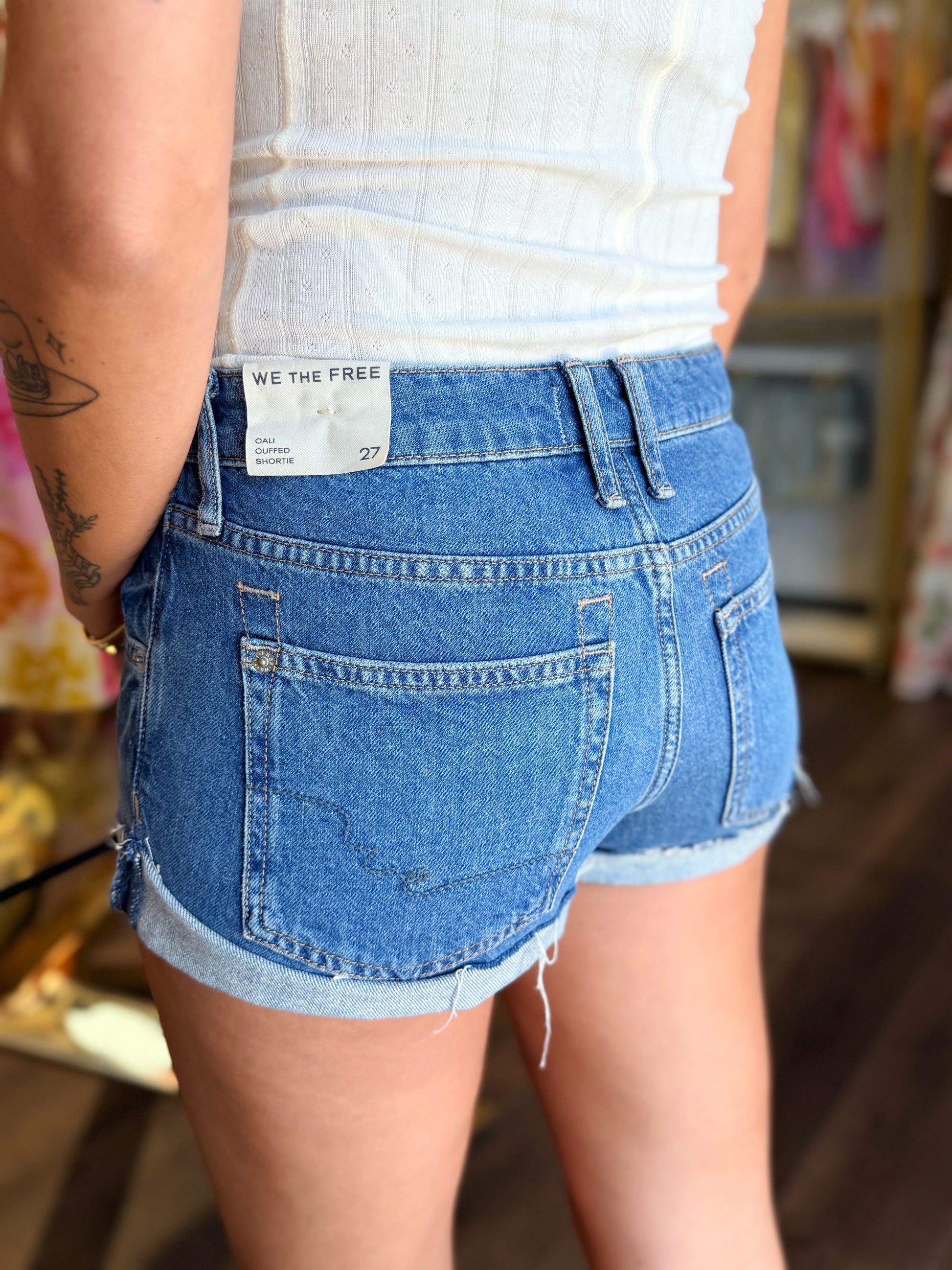 model wearing medium wash denim shorts from the back