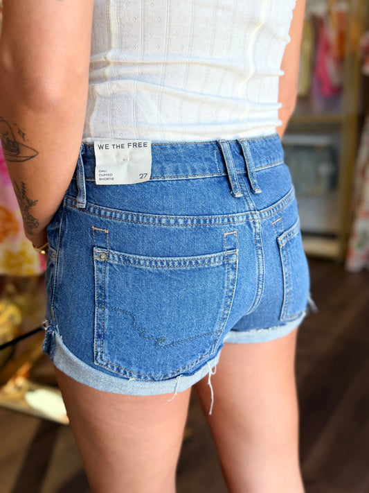 model wearing medium wash denim shorts from the back