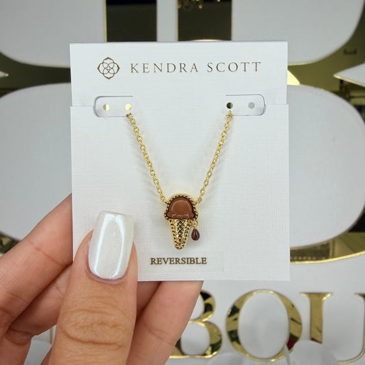Kendra Scott necklace on a card held by a hand with a blurred background