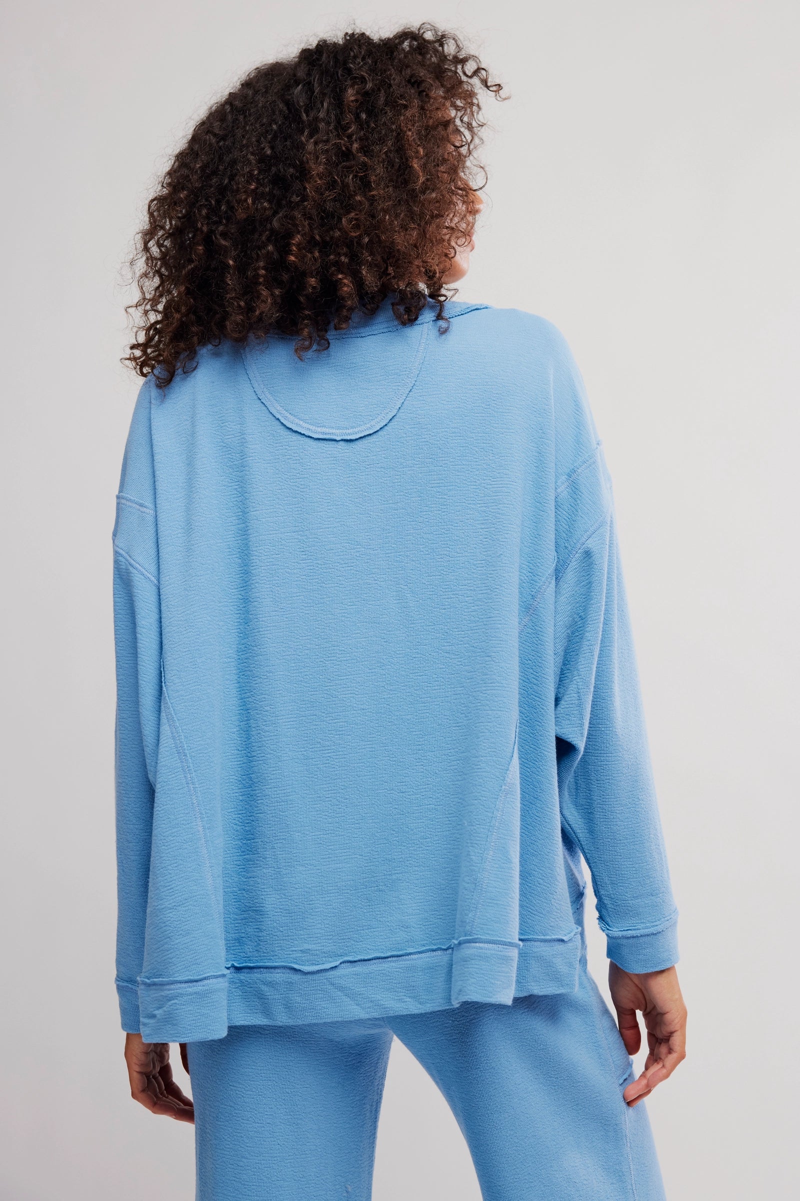 Person wearing a blue sweatshirt and pants on a plain background
