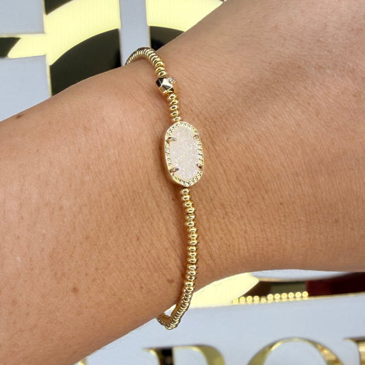 Gold bracelet on a wrist with a decorative background