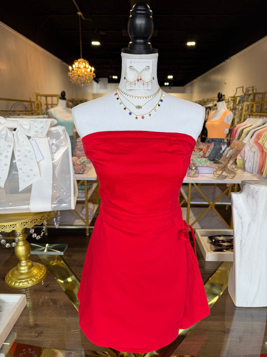 Red dress on a mannequin in a store setting with various items in the background.