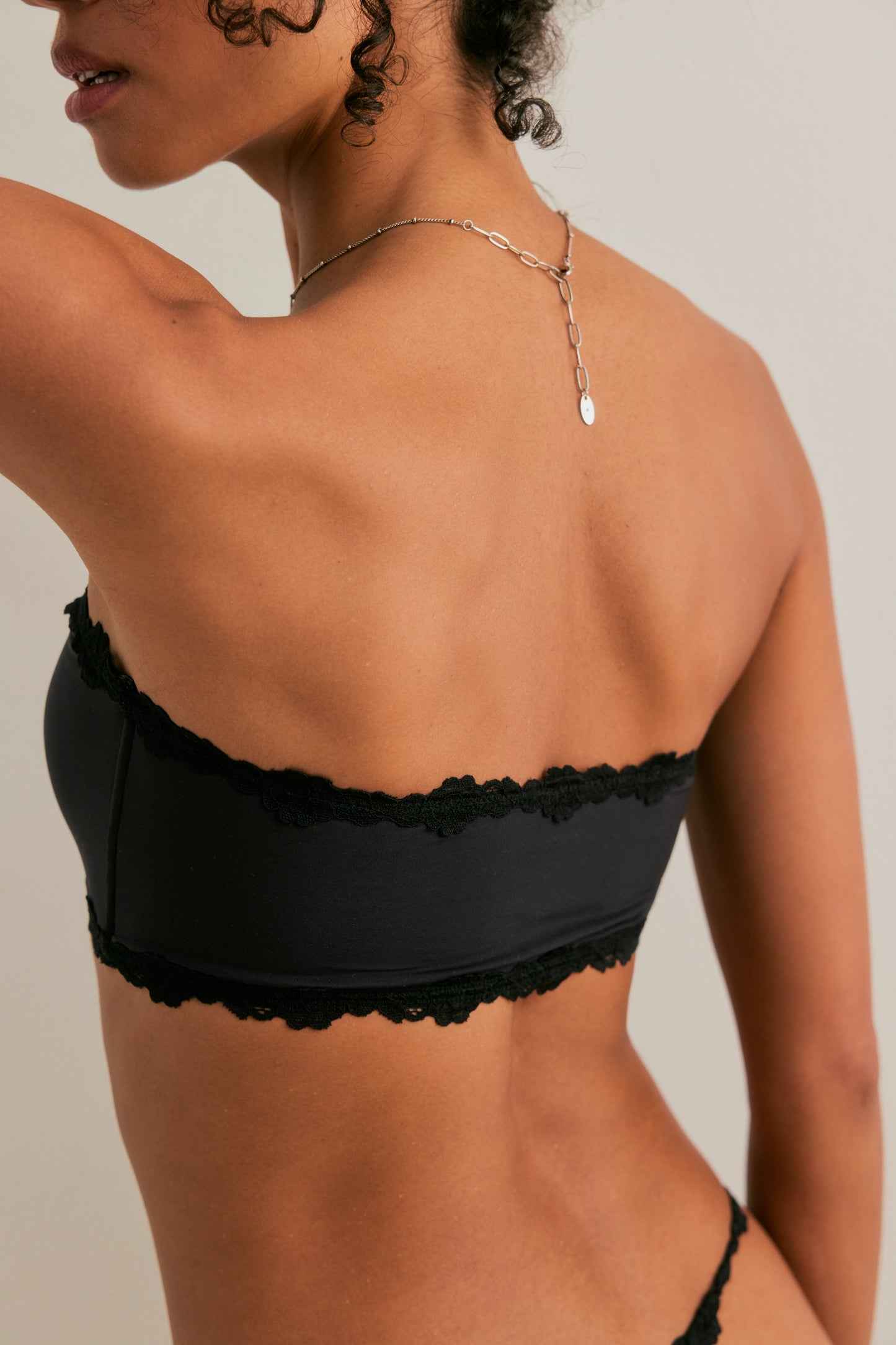 Black lace bralette worn by a person on a neutral background