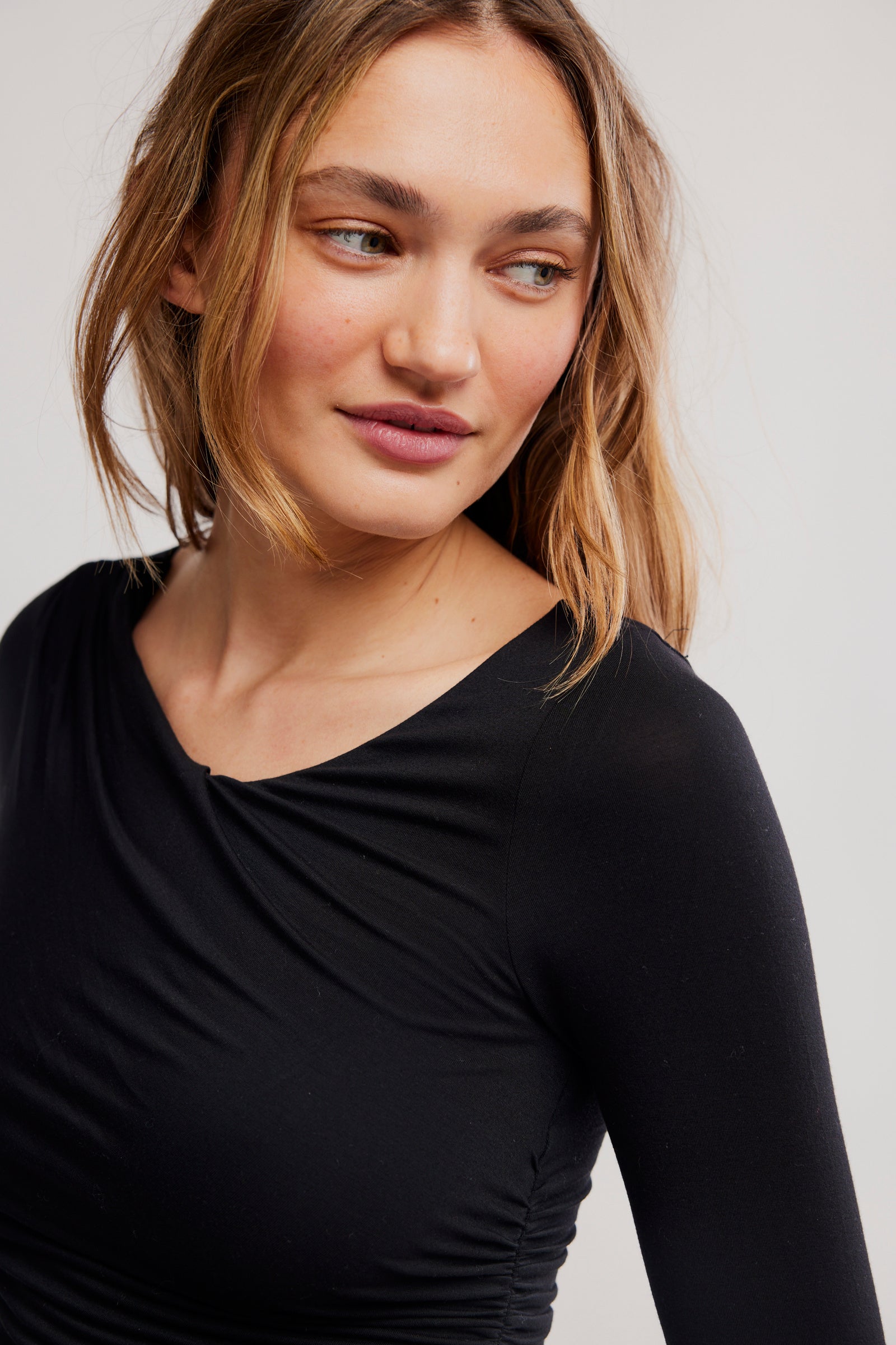 Woman wearing a black long-sleeve top against a plain background