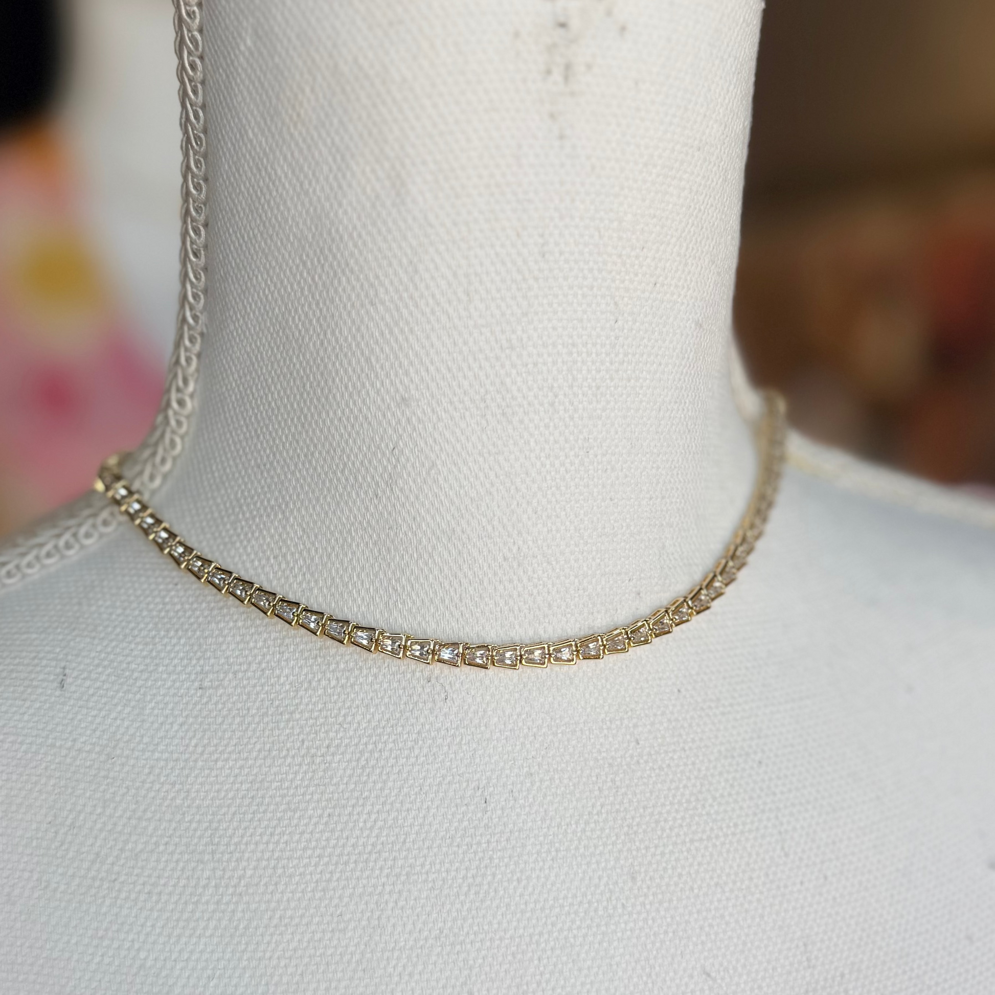 Gold chain necklace on a mannequin with a blurred background
