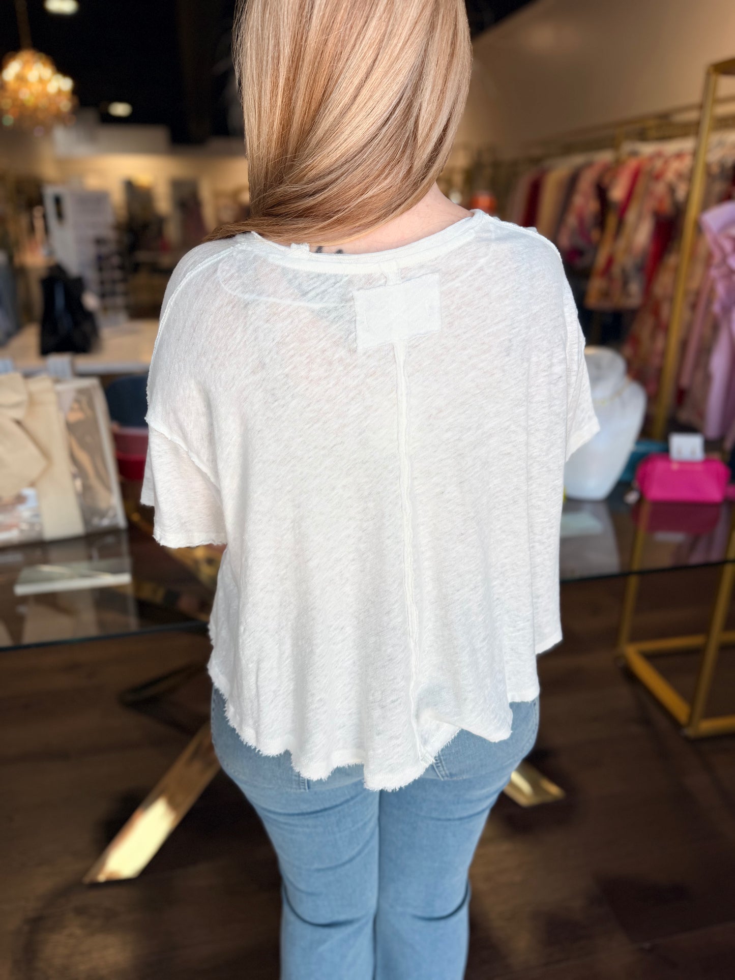 Person wearing a white blouse with sheer back panels in a store setting