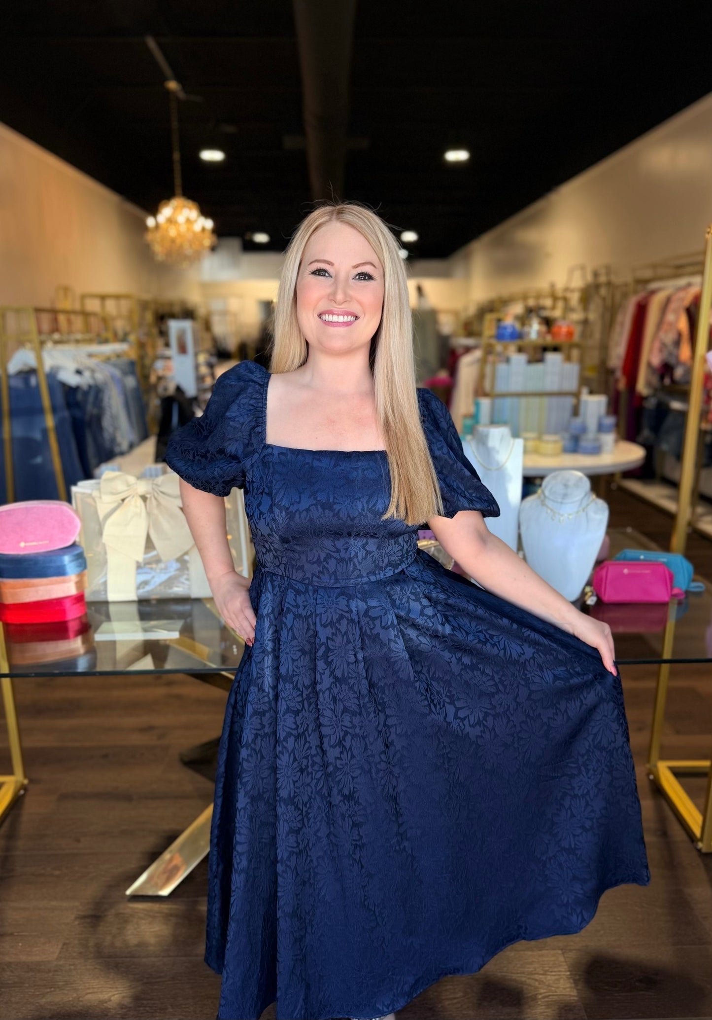 Model standing in front of store in navy midi dress with florals 