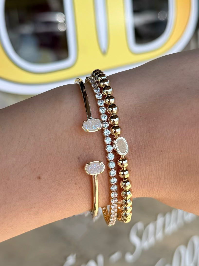 Gold bracelets on a wrist with a blurred background