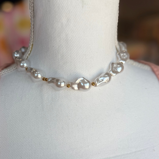 Pearl necklace on a mannequin with a blurred background.