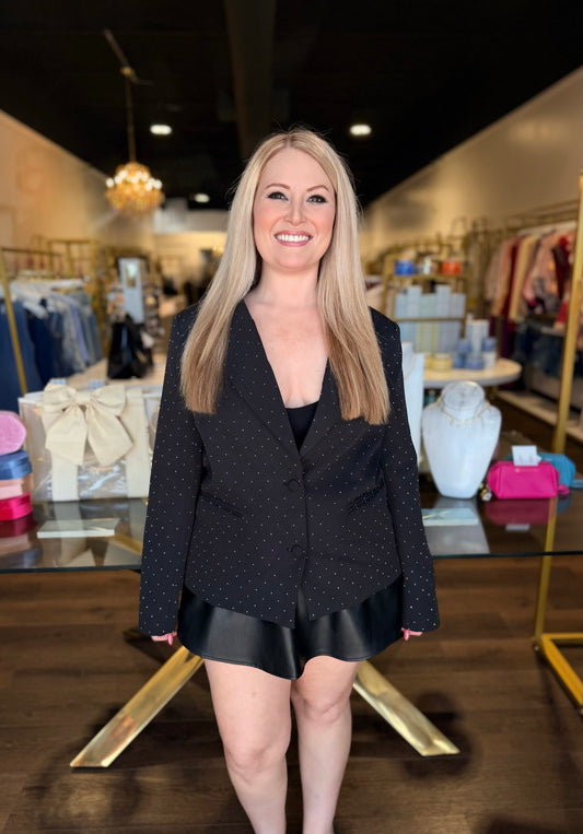 Model standing infront of store in all black with black blazer with rhinestones all over it 