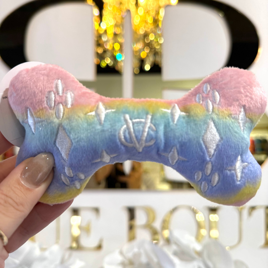 Colorful dog toy with spikes held by a hand in front of a blurred store sign.