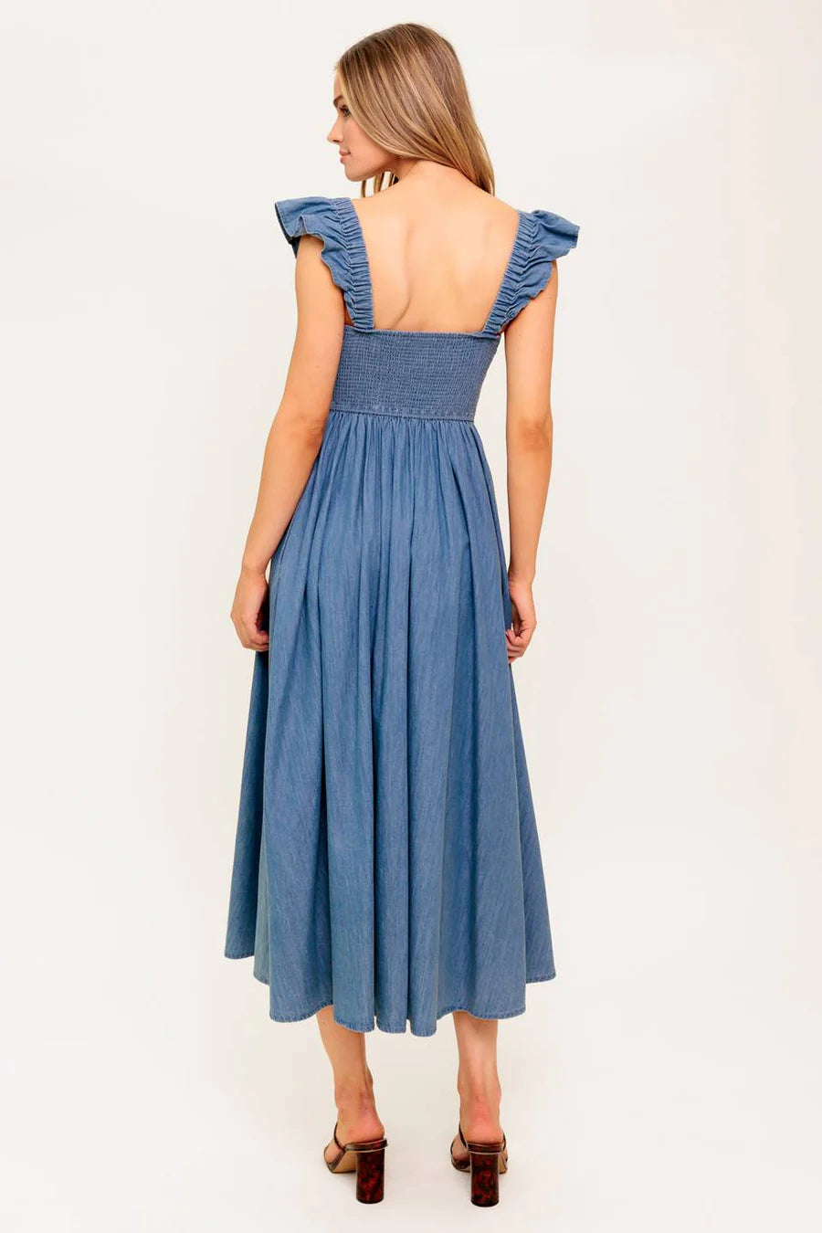 Woman wearing a blue dress with ruffled shoulders on a white background