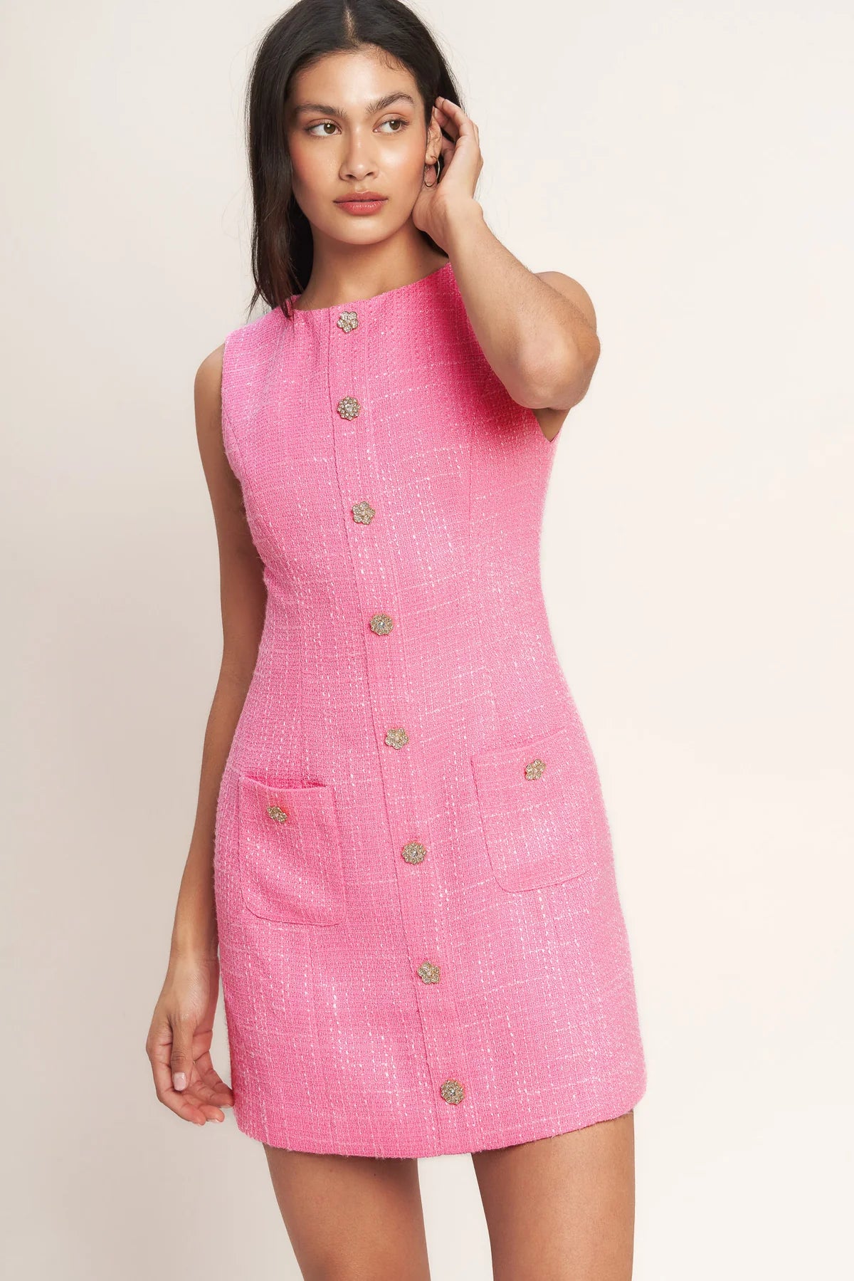 Woman wearing a pink dress with buttons on a beige background