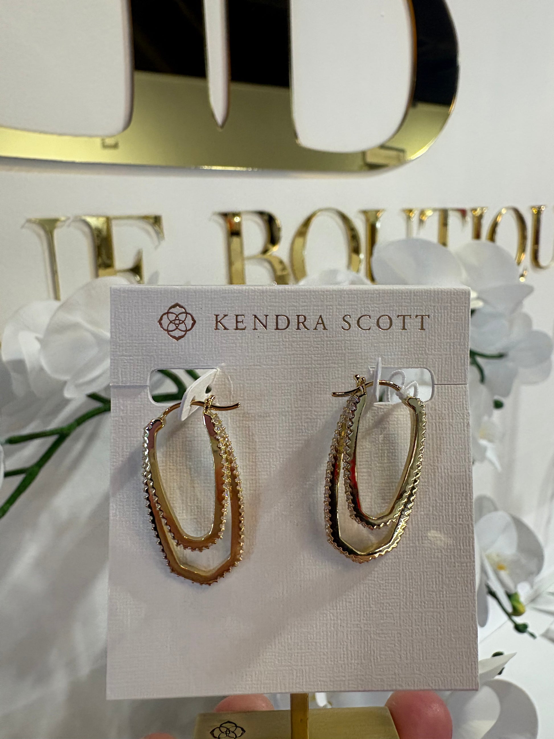 Gold Kendra Scott hoop earrings on a Kendra Scott card with a decorative background
