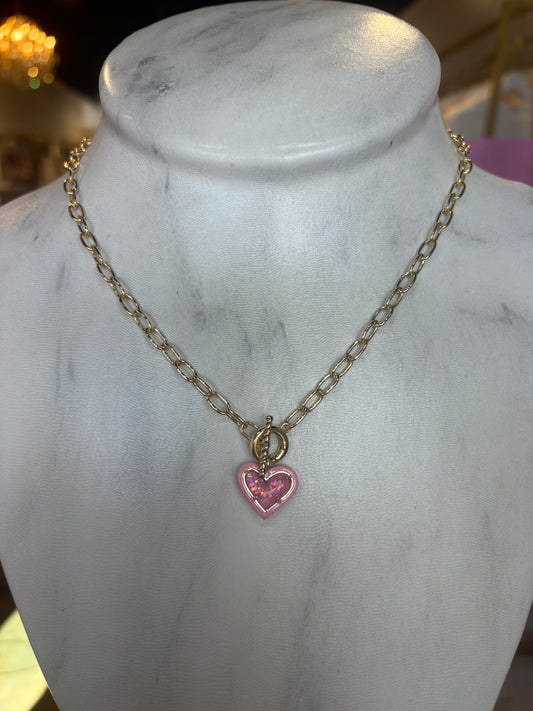 Gold Kendra Scott necklace with a pink heart pendant on a marble mannequin.