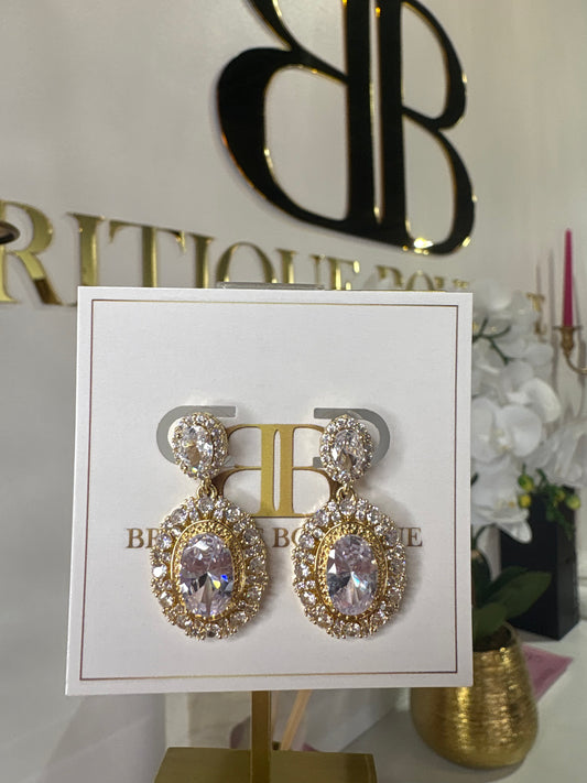 Gold and crystal earrings on a branded card with a decorative background