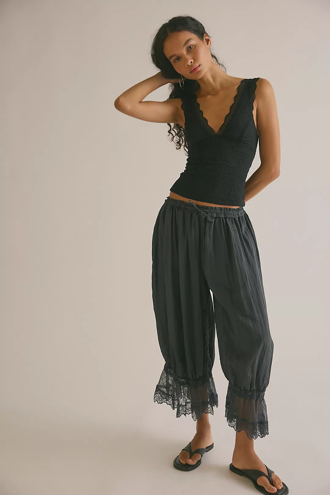 Model wearing black lace tank top with black pants facing forwards