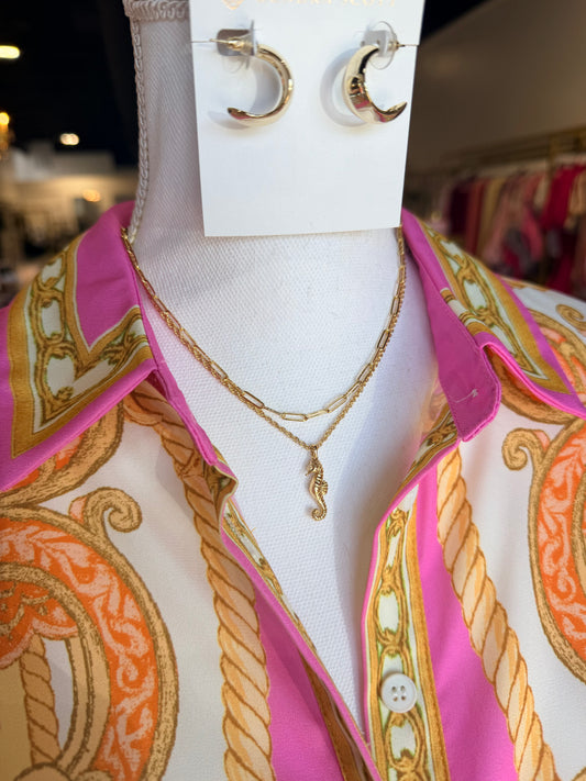 Mannequin wearing a patterned shirt with jewelry on display