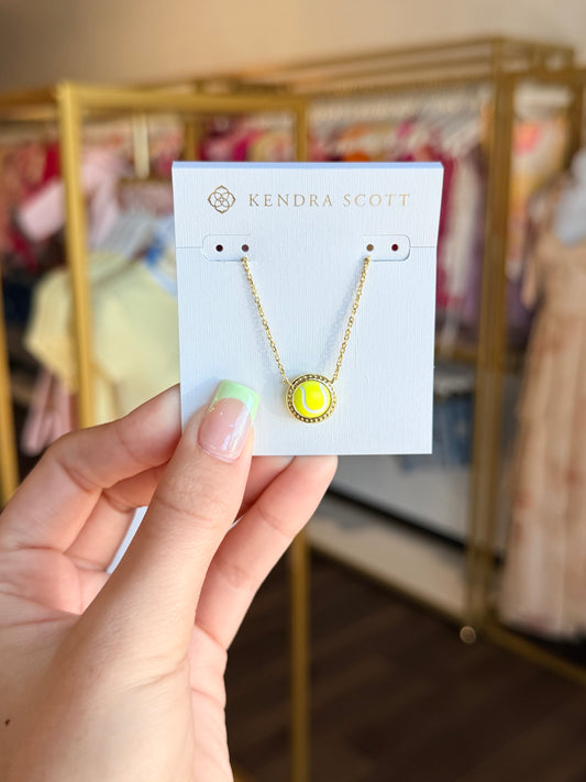 Kendra Scott necklace on a card held by a hand with a blurred store background