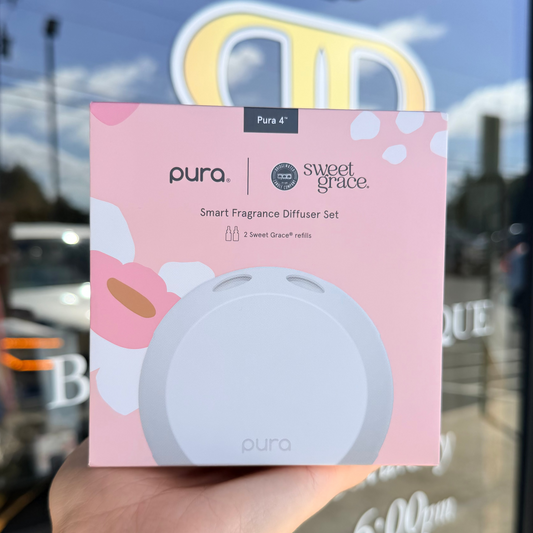 Pura sweet grace smart fragrance diffuser set packaging held in front of a store window.