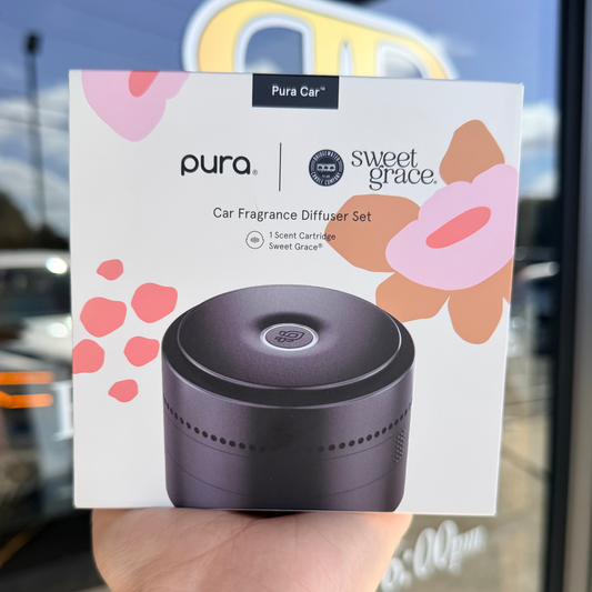 Pura car fragrance diffuser set packaging held in front of a store window.