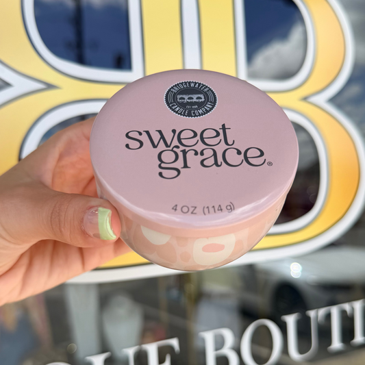 Hand holding a 'sweet grace' product in front of a store sign.