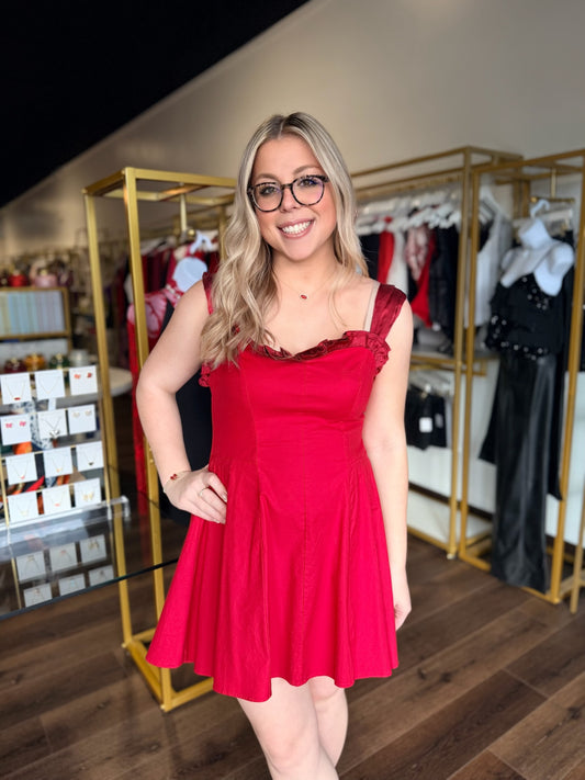 Woman in a red dress standing in a clothing store.