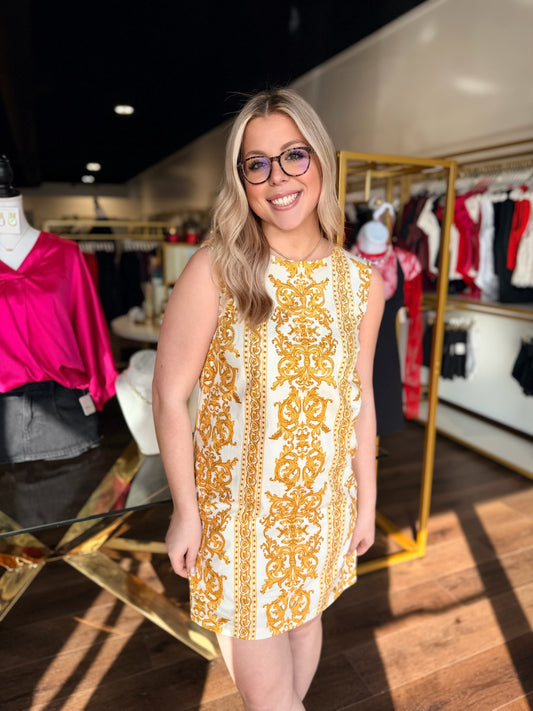 Woman wearing a yellow and white patterned dress in a clothing store.