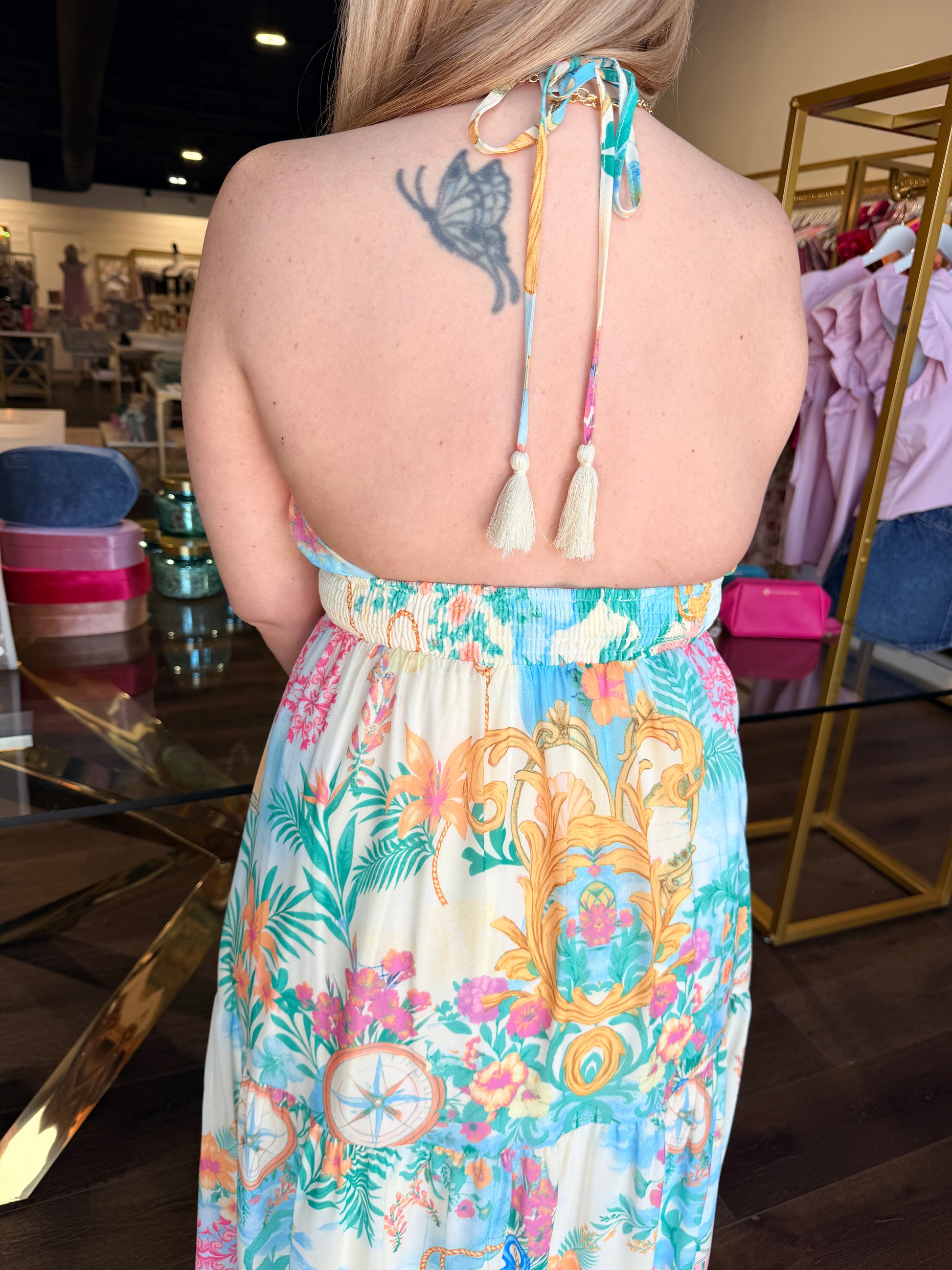 Person wearing a colorful floral dress with a patterned back design in a store setting.