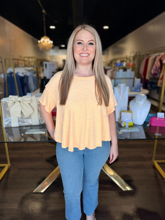 Woman wearing a yellow top and blue jeans in a store setting