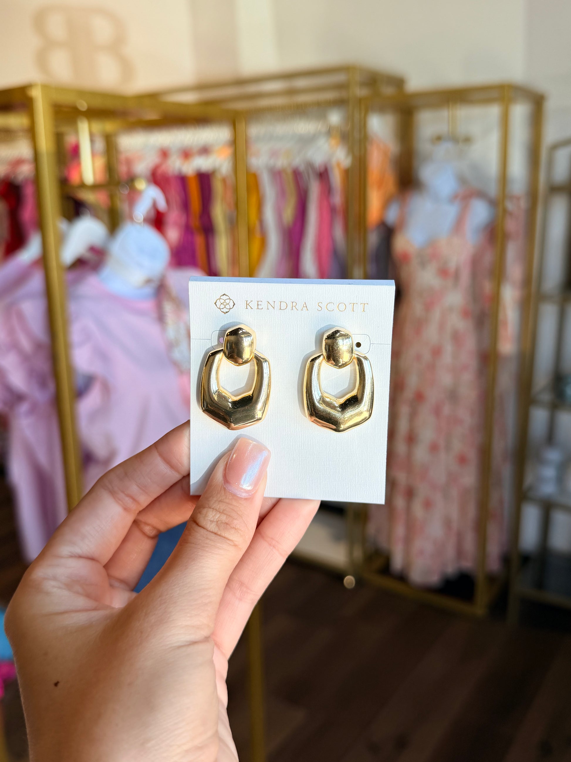 Hand holding Kendra Scott open gram earrings 