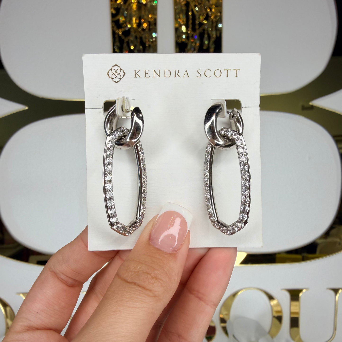 Hand holding Kendra Scott dangle silver earrings 