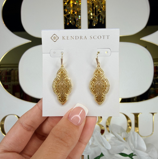 Hand holding Kendra Scott dangle earrings infront of bb 