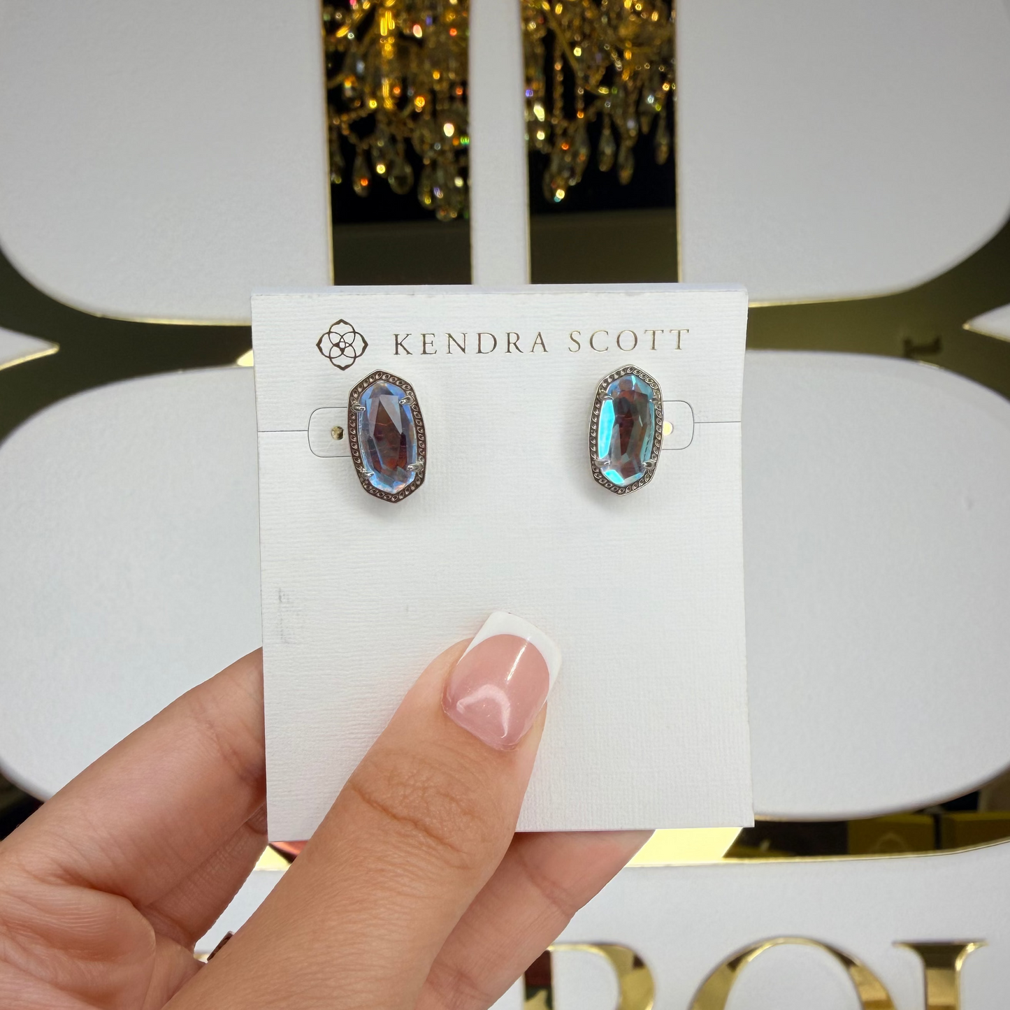Hand holding silver stud Kendra Scott earrings 