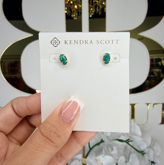 Kendra Scott earrings on a card held by a hand with a blurred background
